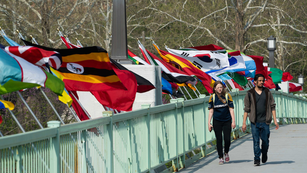 two students walking on bridge with flags