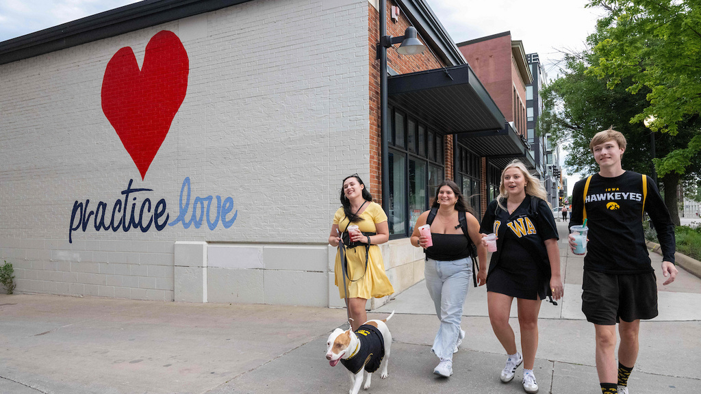 students walking next to mural on building