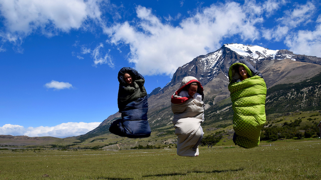 student jumping in sleeping bags