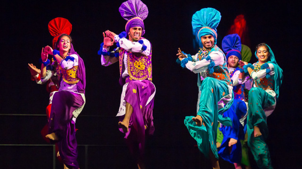 Several performers in colorful outfits dancing on stage