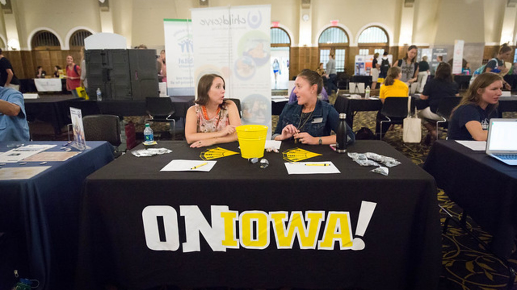 Two people making funny faces at a OnIowa table in the IMU Main Lounge