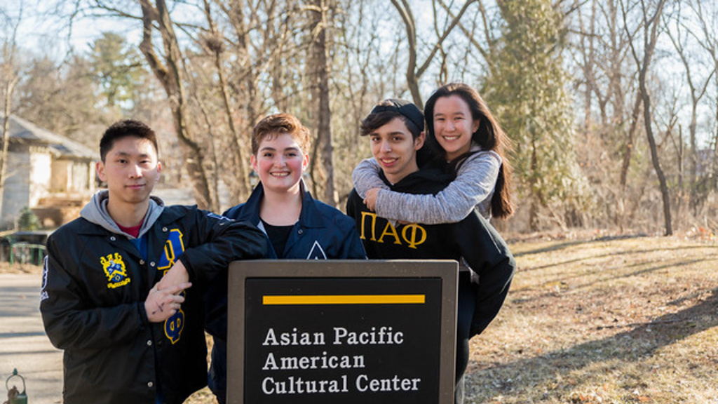 Four people standing in front of the Asian Pacific American Cultural Center sign