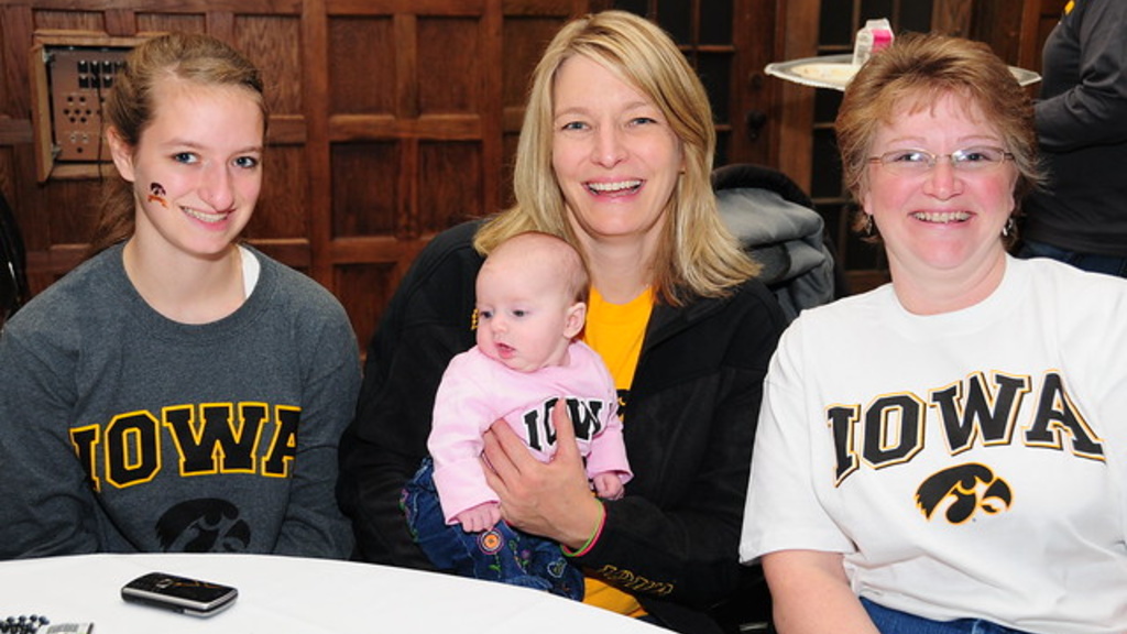 Three adults and a baby wearing Hawkeye sweatshirts